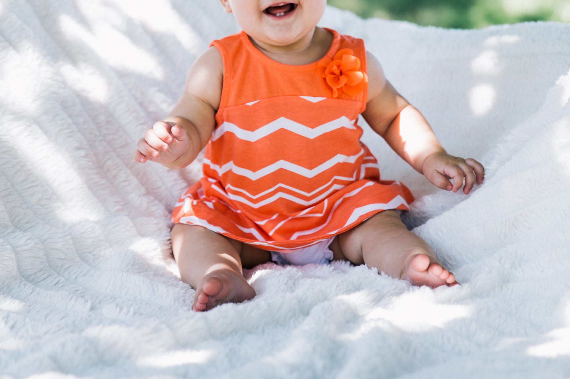 baby-girl-feet_4460x4460 A baby girl in a bright orange dress and bare feet giggling at the camera